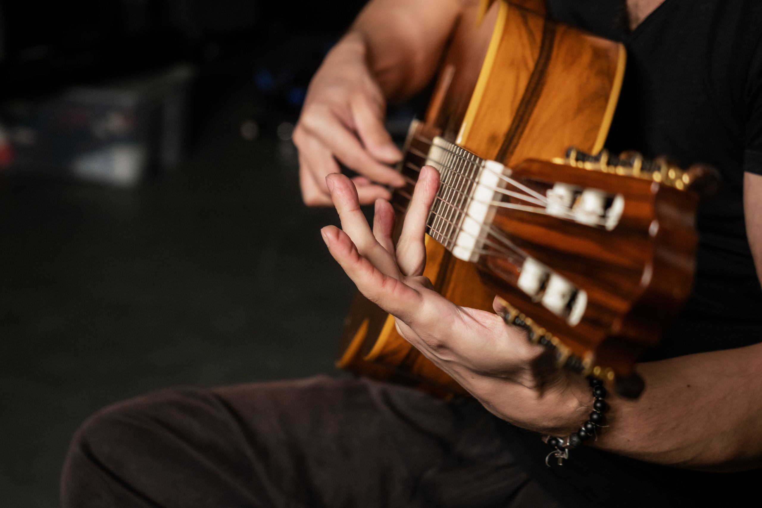 a detailed shot of a musicians hands playing an acoustic guitar showcasing strings and technique. 7715313 scaled A detailed shot of a musician's hands playing an acoustic guitar, showcasing strings and technique.