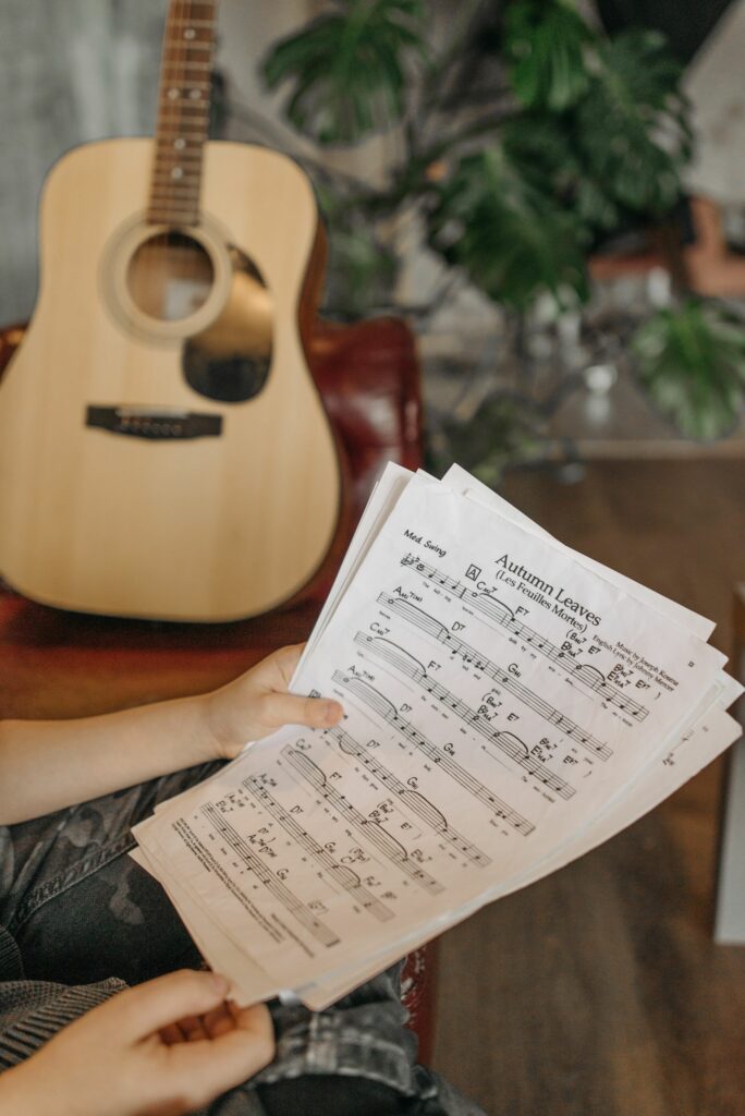 close up of hands holding music sheets with an acoustic guitar in the background. 7520829 scaled Guitar Tab