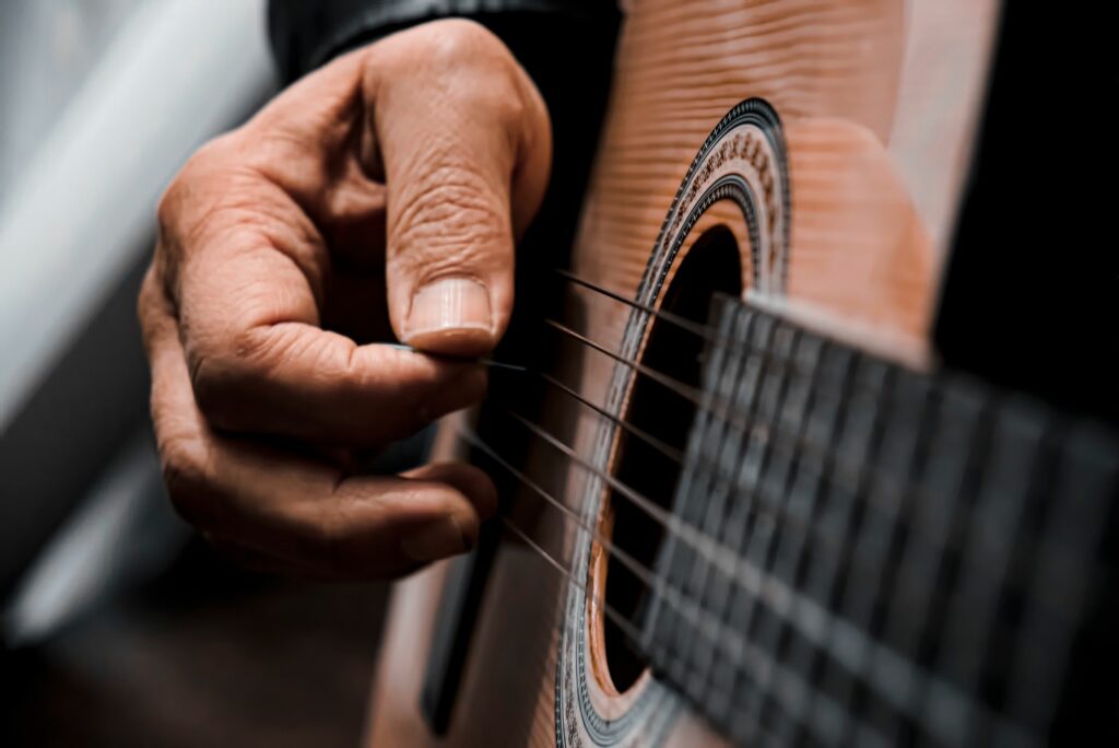 detailed view of a hand strumming acoustic guitar strings highlighting musical expression. 7534935 scaled Detailed view of a hand strumming acoustic guitar strings, highlighting musical expression.
